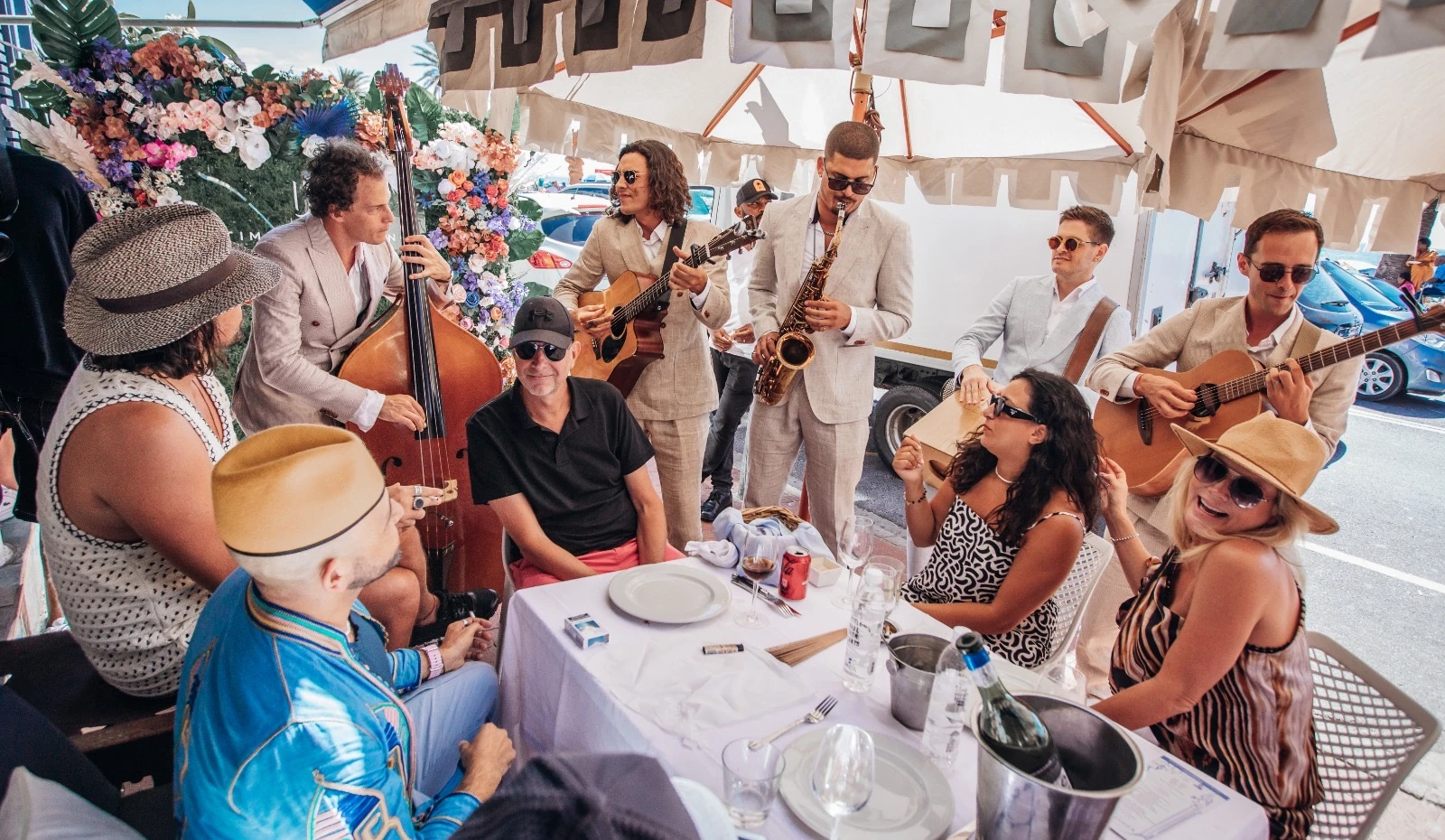 Empire performing acoustically around a table of guests at a daytime celebration