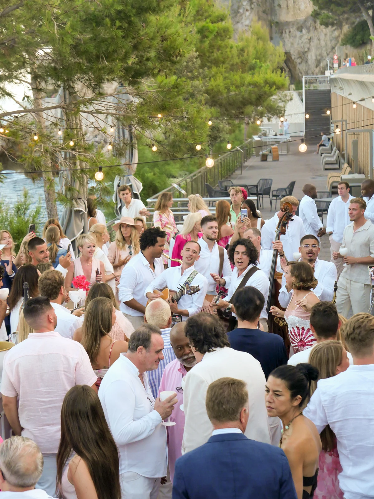 Empire performing among guests at an outdoor private celebration under string lights